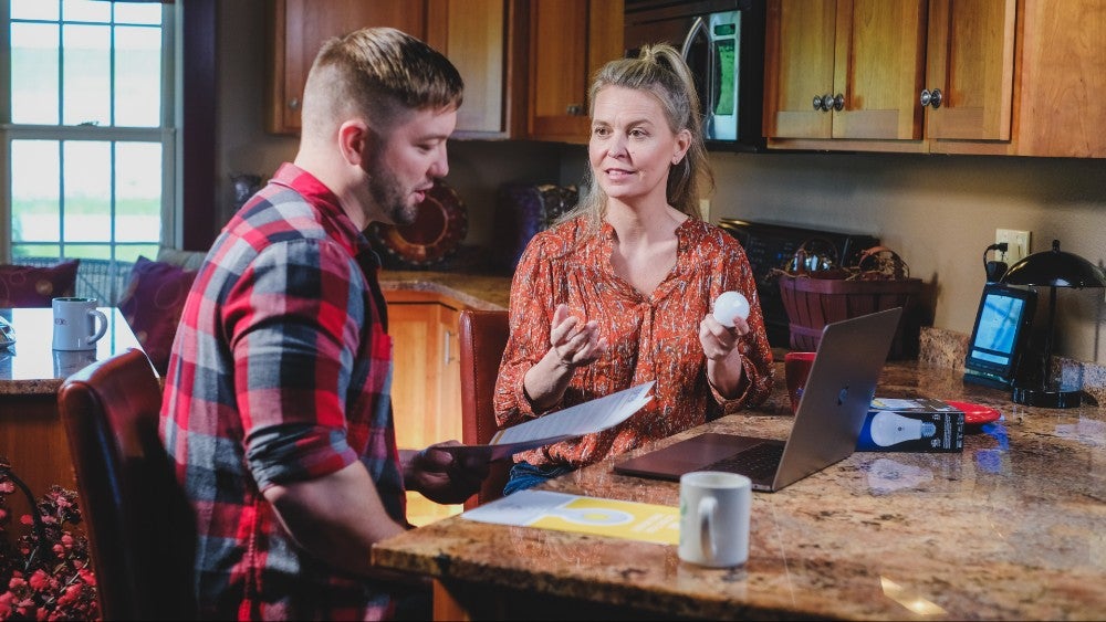 man and lady discussing electricity savings with different types of bulbs