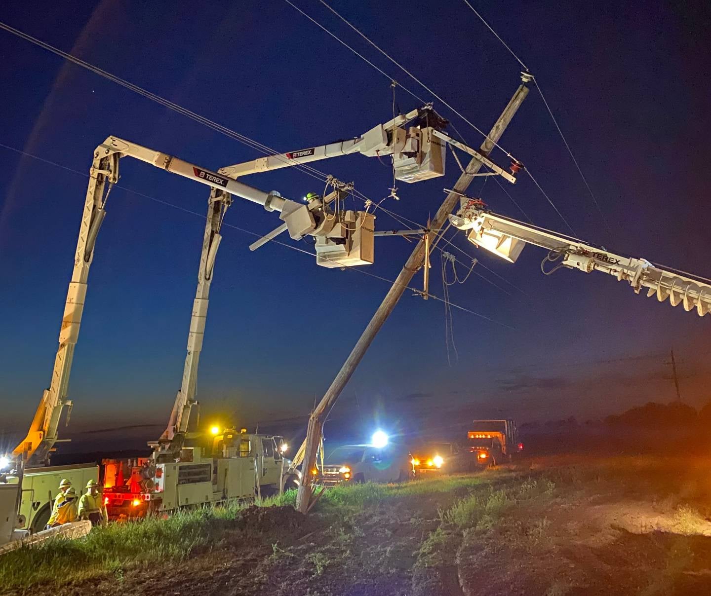 Outage crews at night in bucket trucks fixing a falling line